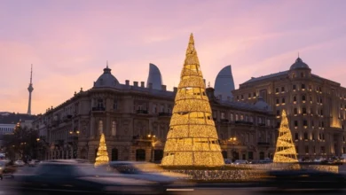 Golden Christmas decorations in Baku with historic architecture and modern Flame Towers at sunset.